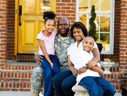 African American Family sitting on bench in front yard.  Focus on mother.